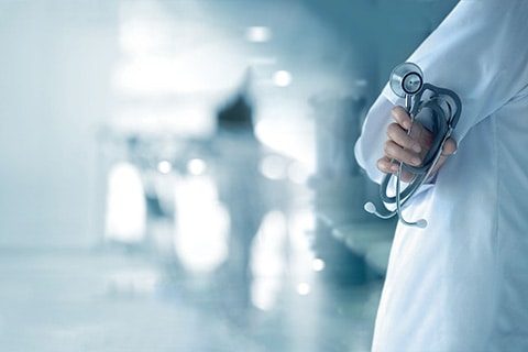 Doctor with stethoscope in hand on hospital background, medical and medicine concept