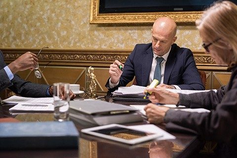 Mature and experienced lawyers in formalwear highlighting the main points of juridical documents while co-working by table