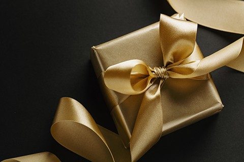 Christmas conceptual background with golden gift with ribbon on dark. Top View