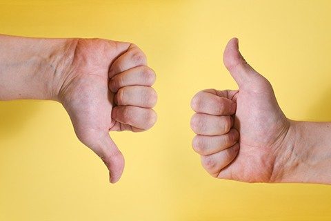 Likes and dislikes the hand gesture, a young male hand close-up. Isolated on a yellow background photo