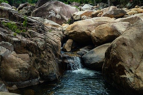 A small cascade surrounded by big boulders at Ba Ho Waterfalls Cliff Jumping in Khanh Hoa Province, Vietnam
